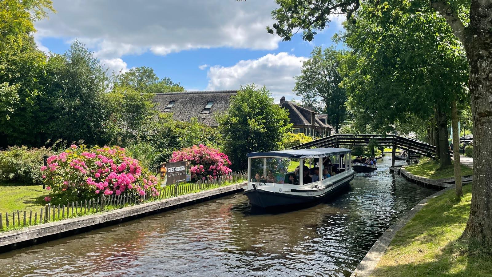 Canal cruise boat passing traditional houses in Giethoorn Netherlands