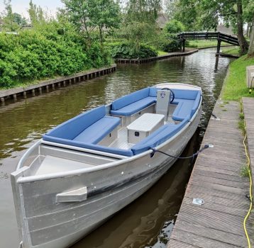 Electric boat moored at wooden dock in Giethoorn canal