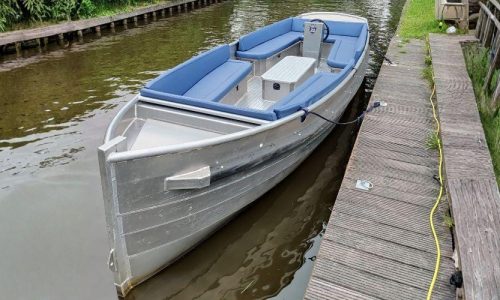 Electric rental boat docked at wooden pier in Giethoorn